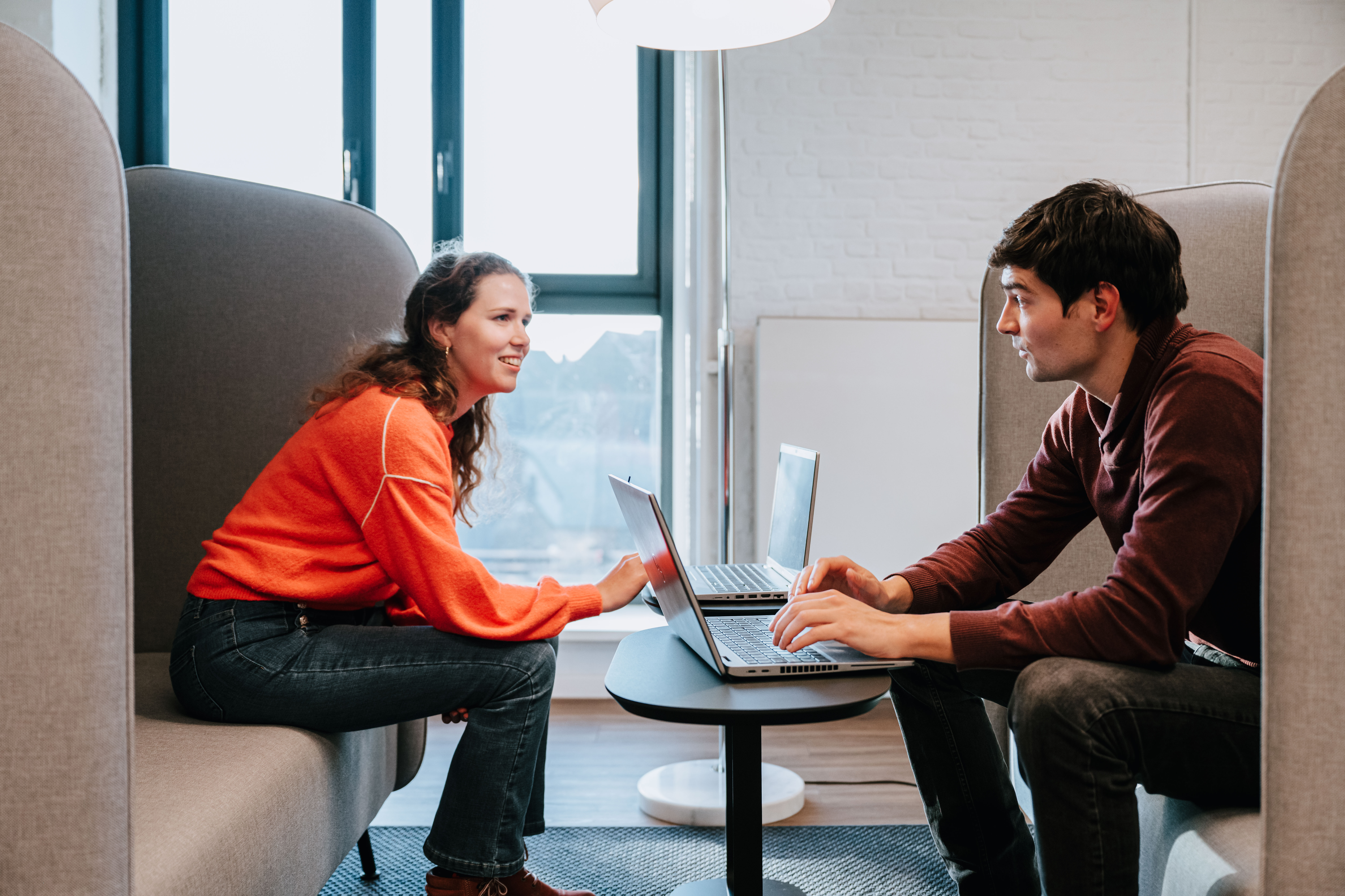 Two people sitting across from each other in a focused working booth