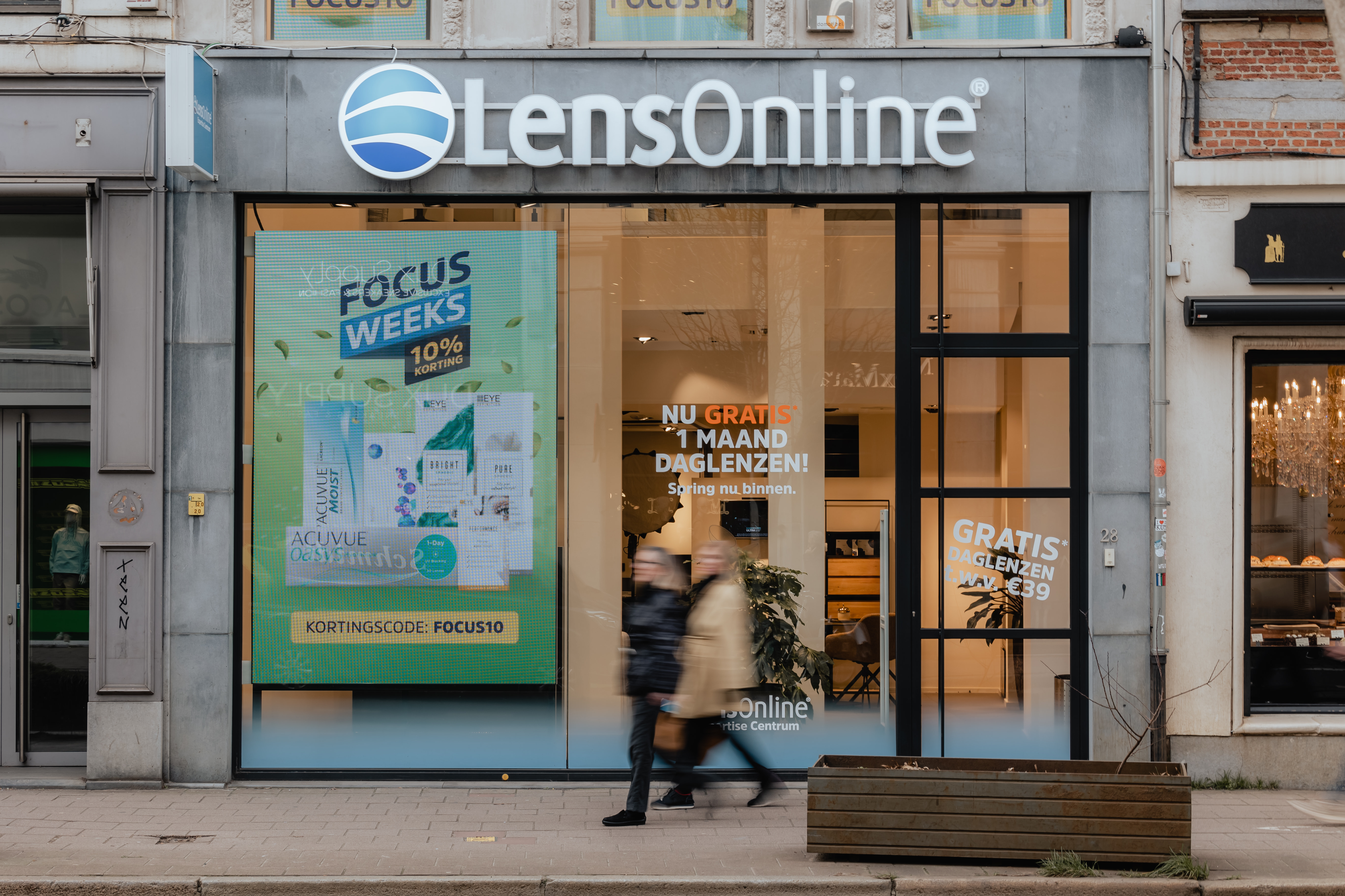 Two people walking past a LensOnline store
