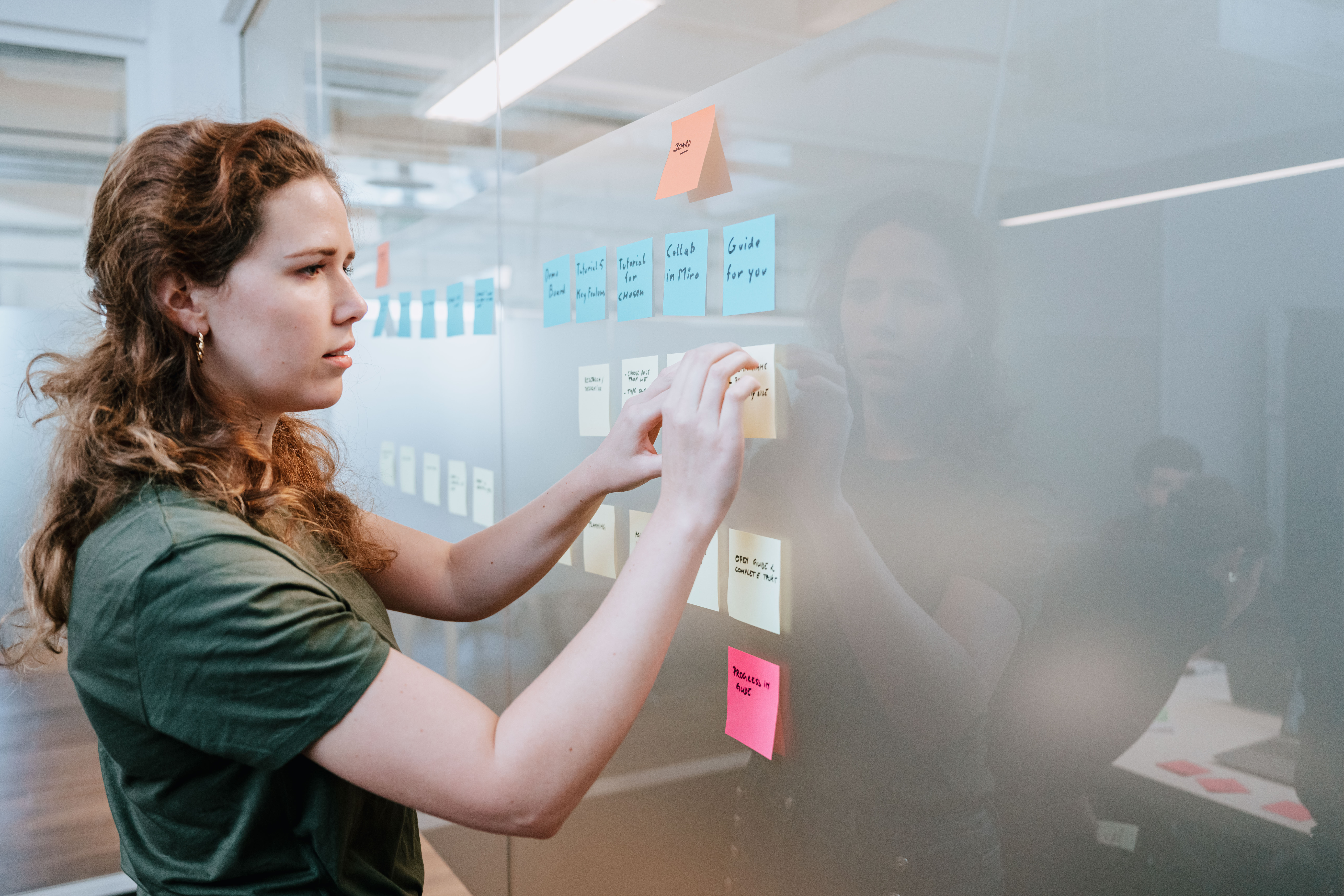 A person hanging a sticky note on the wall