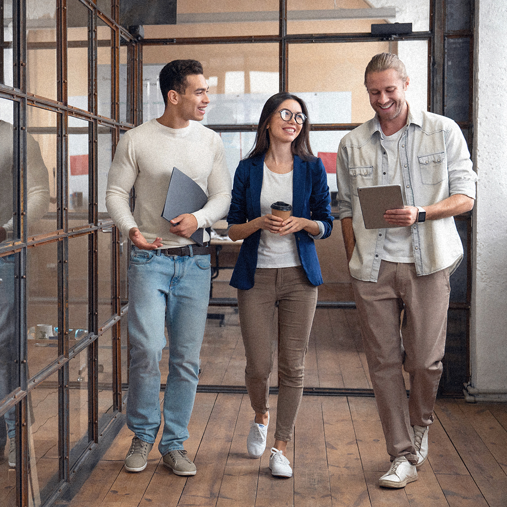Three people walking out of a meeting, talking with each other in the hallway