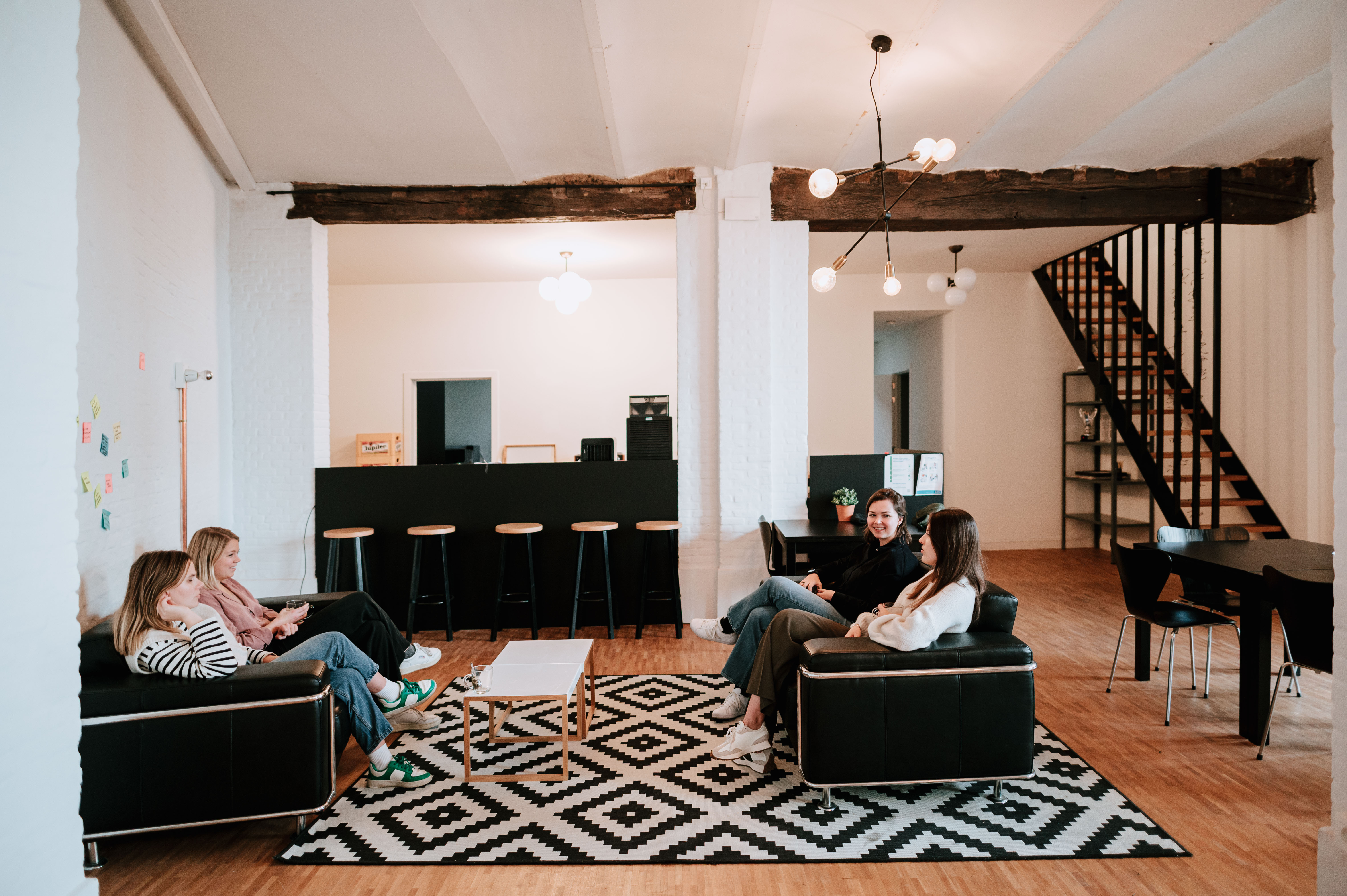 Wide shot of an office space with four people sitting in a couch
