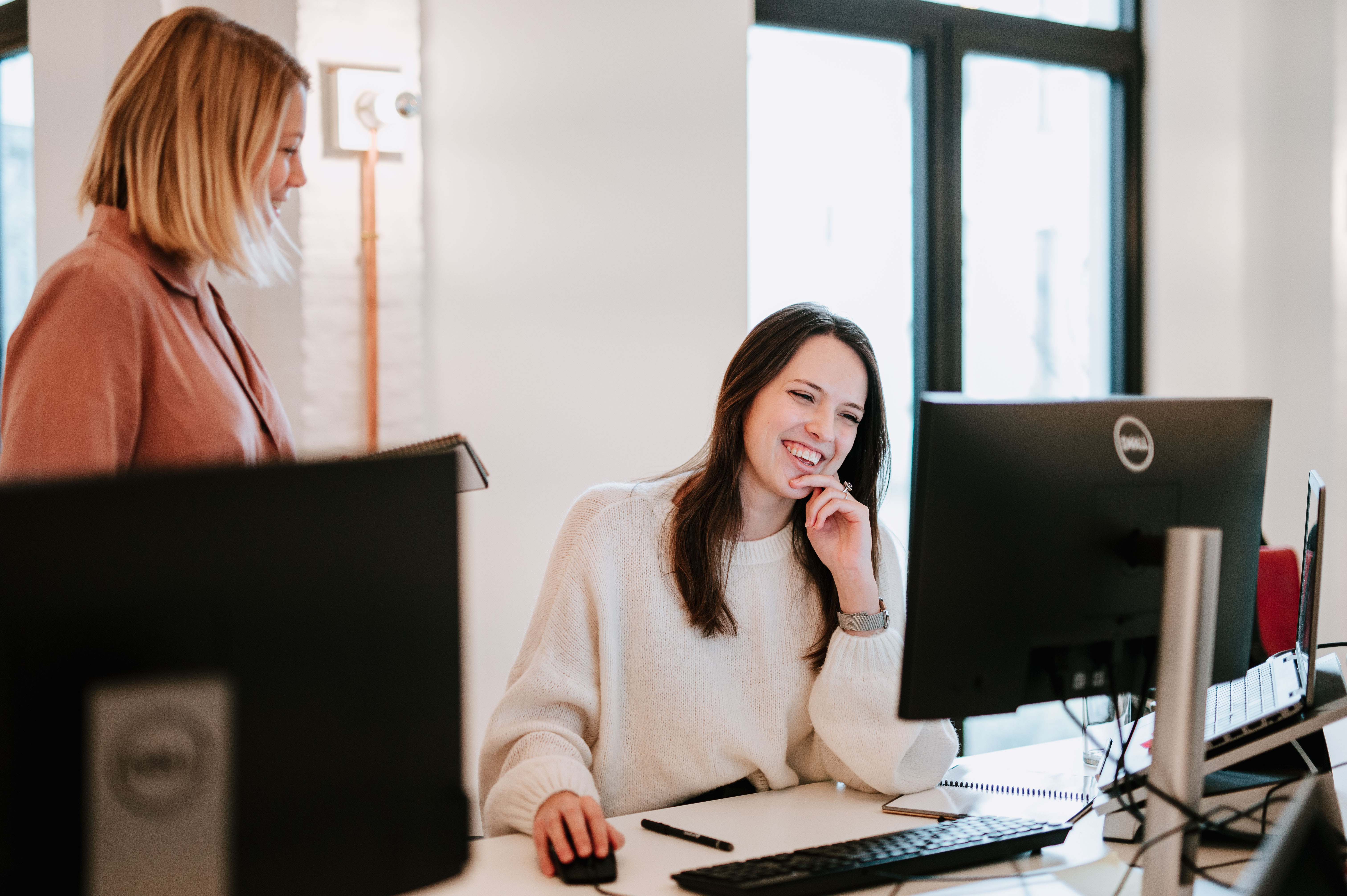 Two people in conversation, laughing, sitting at a desk