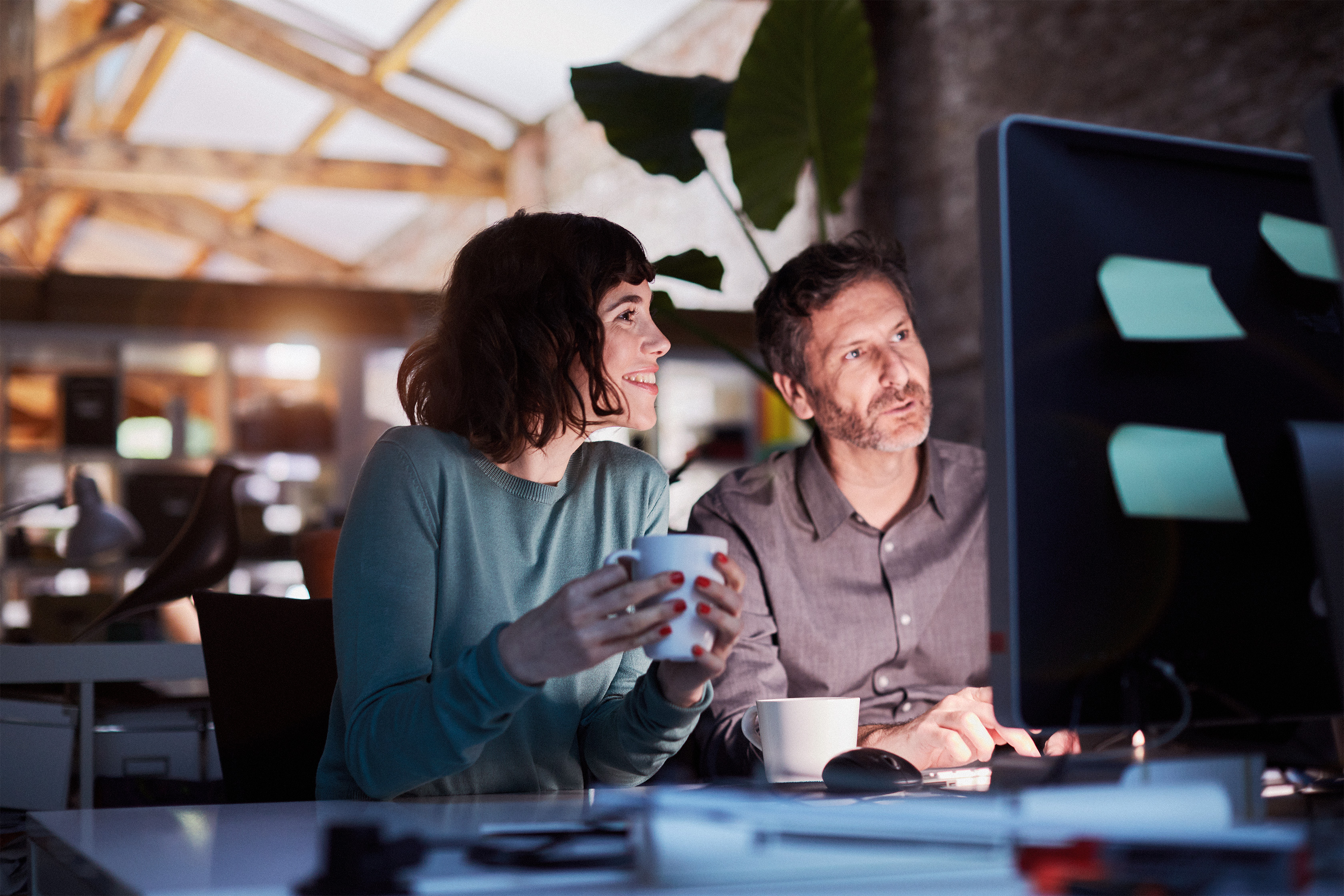 Two people in an office space looking at a desktop screen